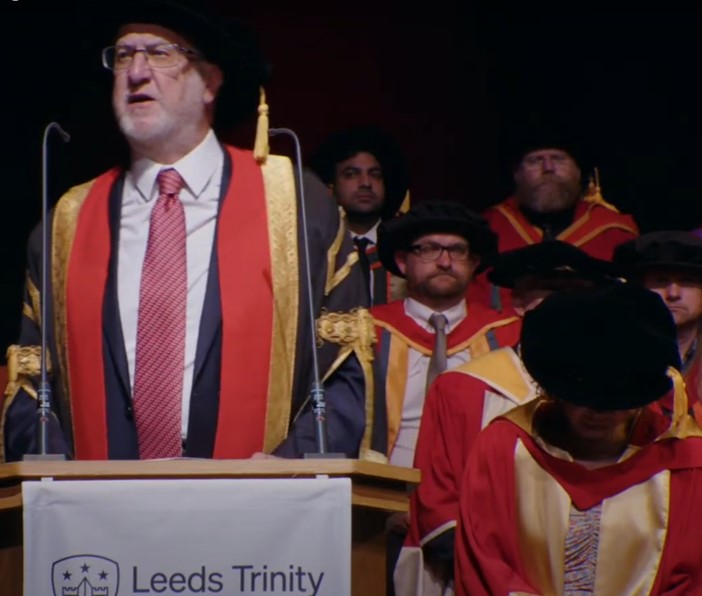 John Battle speaking at a podium